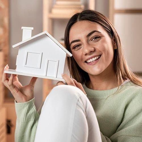 A homebuyer holding a small model house